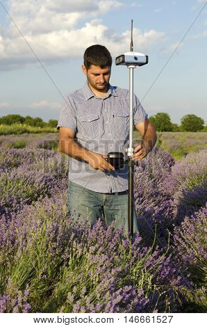 Surveyor adjusting its instrument in a field of lavender