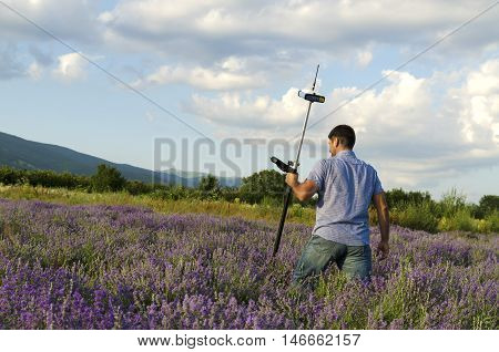 Land surveyor crossing lavender field with controller