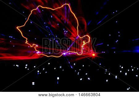 A laser show rendition of the Romanian map. Drawn in the air like a computer graphic location is an outdoor night party. Abstract
