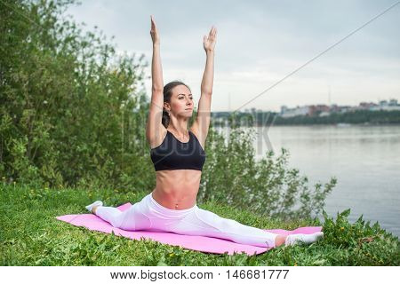 Woman practicing yoga in nature hanumanasana monkey pose