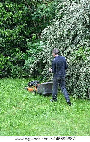 Verneuil sur Seine France - june 27 2016 :a man is cutting lawn in a garden