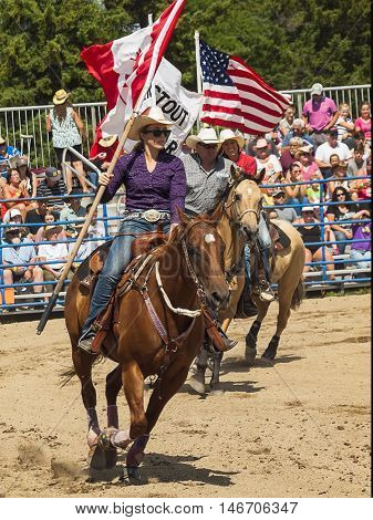 Rodeo. A man and a woman with the flags of Canada and America on horseback. Winnipeg. Canada.