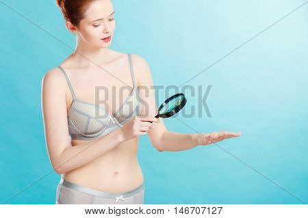 Woman Using Magnifying Glass To Examine Her Moles Skin