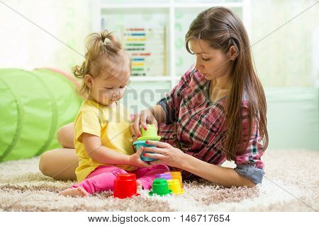 babysitter with kid girl playing in nursery