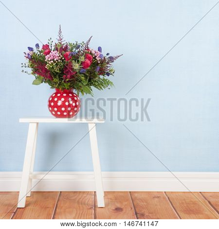 Vase mixed bouquet flowers on blue background