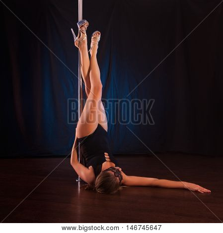 sexy young slender brunette dancing on the pole. Female caucasian appearance with an excellent bum shows tricks on the pole