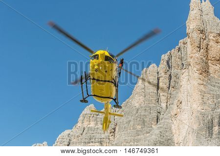 Medical rescue helicopter flying rescue injured climber on the Tre Cime. Italy, Dolomites