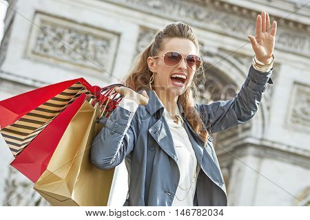 Smiling Woman With Shopping Bags In Paris, France Handwaving
