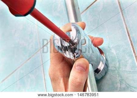 Residential plumbing repair replacing the plumbing in the bathroom close-up of hands handyman with red phillips screwdriver install adjustable shower slide rail bar bracket.