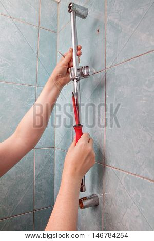 Replace broken wall mounted vertical height adjustable shower bar slider rail holder close-up of hands remove the faulty slide rail.