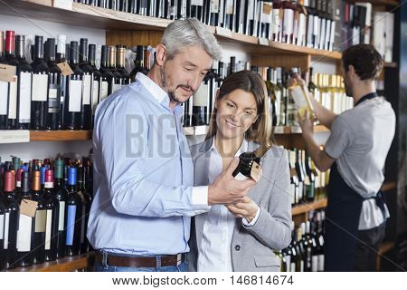 Couple Looking At Wine Bottle In Store