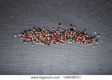 colored peppers scattered on the slate top view