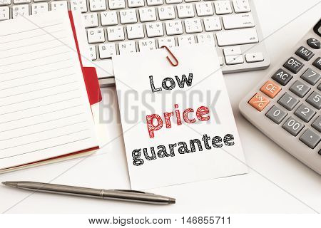 Word text Low price guarantee on white paper card on office table / business concept