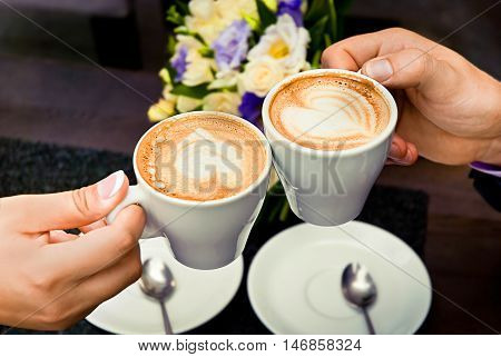 Man and woman's hands and coffee cups with hearts