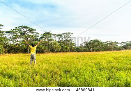 Young man in spreading hand in green meadow.