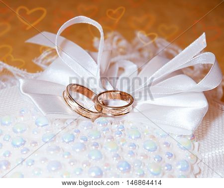 Gold wedding rings on the pincushion. Background with hearts