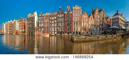 Panorama of beautiful typical Dutch dancing houses at the Amsterdam canal Damrak in sunny day, Holland, Netherlands.