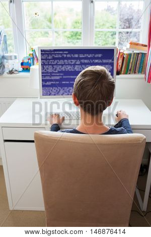 Teenage Boy In Bedroom Writing Computer Code