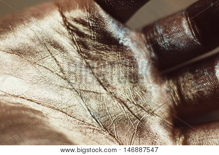 Close-up photo of golden human hand. Patterns on painted palm with gold dust. Luxury design of greasepaint, ceremonial body art