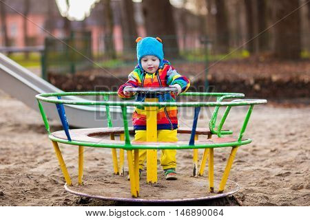 Little boy on a playground. Child playing outdoors in autumn. Kids play on school yard. Happy kid in kindergarten or preschool. Children having fun at daycare play ground. Toddler on a swing.