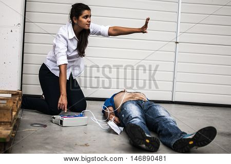 girl using a defibrillator for an unconscious man