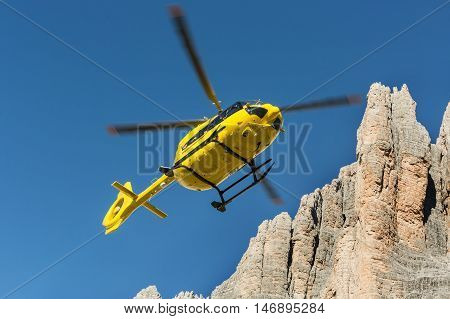 Medical rescue helicopter flying rescue injured climber on the Tre Cime. Italy, Dolomites