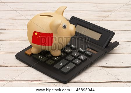The Chinese yuan currency A golden piggy bank and calculator on a wood background with Chinese flag