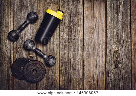 Old iron dumbbells or exercise weights with extra plates on an old wooden deck, floor or table. Image taken from above, top view. A lot of copy space around product
