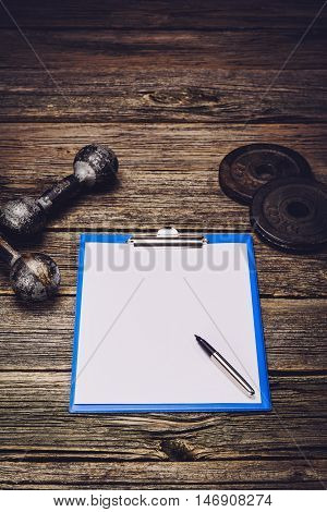 Old iron dumbbells or exercise weights with extra plates on an old wooden deck, floor or table. Image taken from above, low angle or top view. A lot of copy space around product