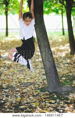 Attractive young girl hanging on the tree in autumn park