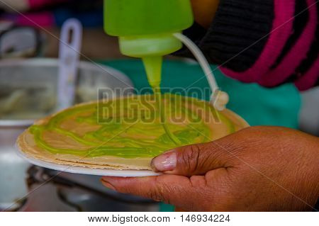 PASTO, COLOMBIA - JULY 3, 2016: woman adding some kiwi syrup to a wafer in a location close to la cocha lake.