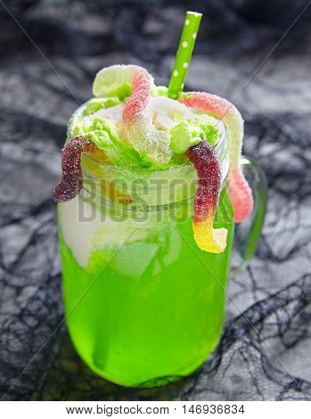 Green drink with ice cream float and gummy worms for Halloween