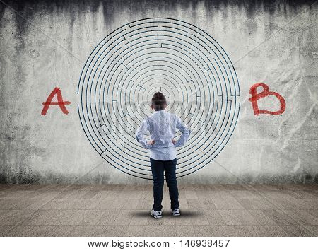 Business concept. Back view of boy looking at a maze on wall point a to the point b