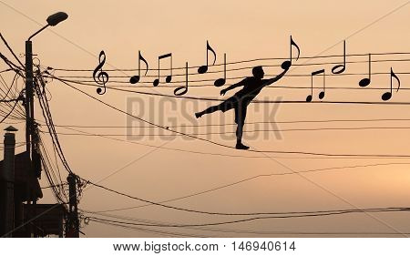Sillouthe of a man putting music notes on wires . Concept of a crazy composer