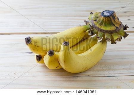 Four remain ripe bananas on a cluster of them on wooden background selective focus .