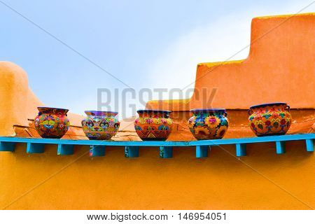 Colorful pots placed on an outdoor shelf taken on an adobe style building taken in New Mexico