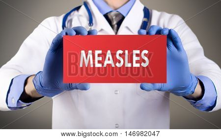 Doctor's hands in blue gloves shows the word measles. Medical concept.