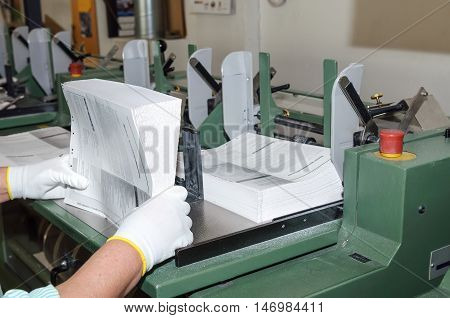 Binding of brochures in printing house. Closeup