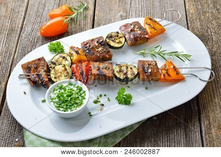Vegan Meal: Grilled Skewers With Mixed Vegetables And Seitan Served  On A White Plate With A Herb So