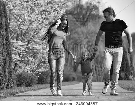 Full-fledged Family. Stylish Family Couple Of Young Pretty Woman And Handsome Man Walking In Park Wi