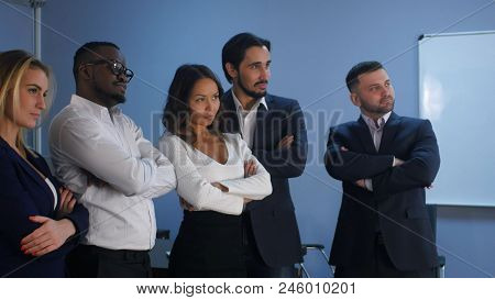 Business Team Standing With Serious Look In Office. Professional Shot