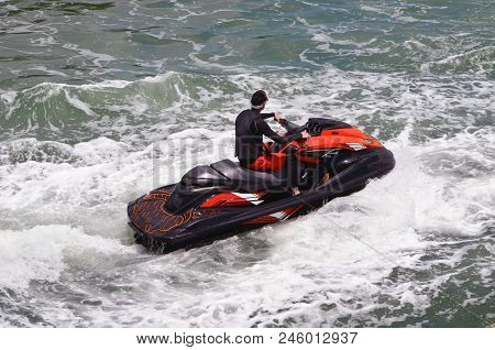 Jet Skier On A Red And Black Jet Ski Riding Waves Off Miami Beach On The Florida Intra-coastal Water