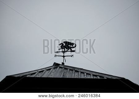 Black Dragon Wind Vane Against The Sky. Weather Vane On Roof Of The Building.
