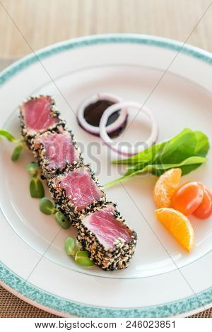 Seared tuna with sesame seeds with green salad on white plate