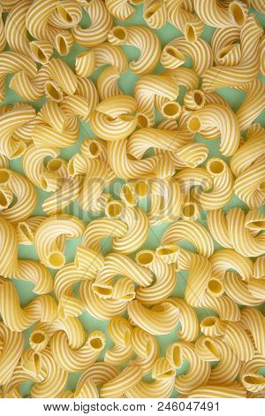 Ellow Background Of Pasta In The Form Of Tubes Spun In A Spiral