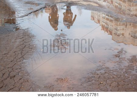 Dangerous Destroyed Roadbed. The Bad Asphalted Road. Big Pothole Filled With Water. Mirror Reflectio