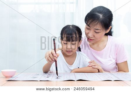 Asian Chinese Mother Teaching Daughter Practice Chinese Calligraphy At Home