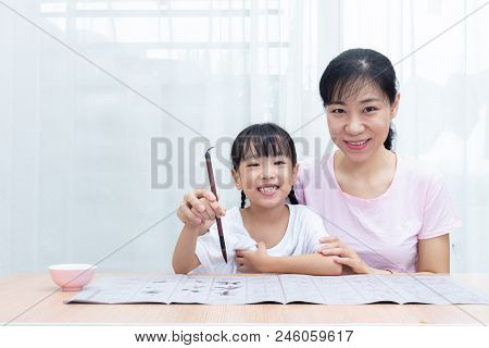 Asian Chinese Mother Teaching Daughter Practice Chinese Calligraphy At Home