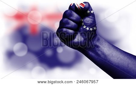 Flag Of Cook Islands Drawn On Male Fist, Strength, Power, Concept Of Conflict. On A Blurred Backgrou