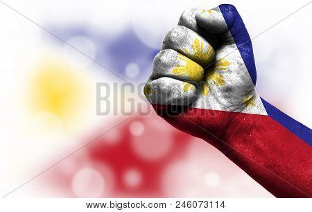 Flag Of Philippines Painted On Male Fist, Strength, Power, Concept Of Conflict. On A Blurred Backgro